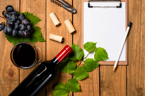 glass of wine with grape bunch and vine leaves and notepad
